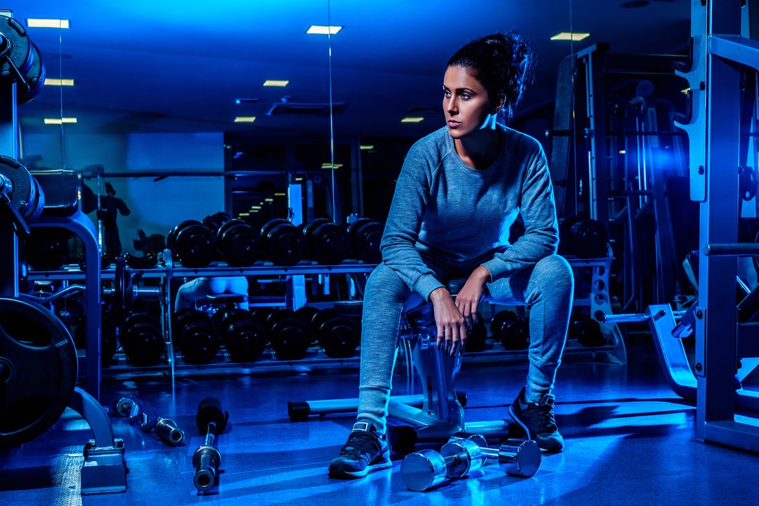 Fit girl sitting on the gym bench